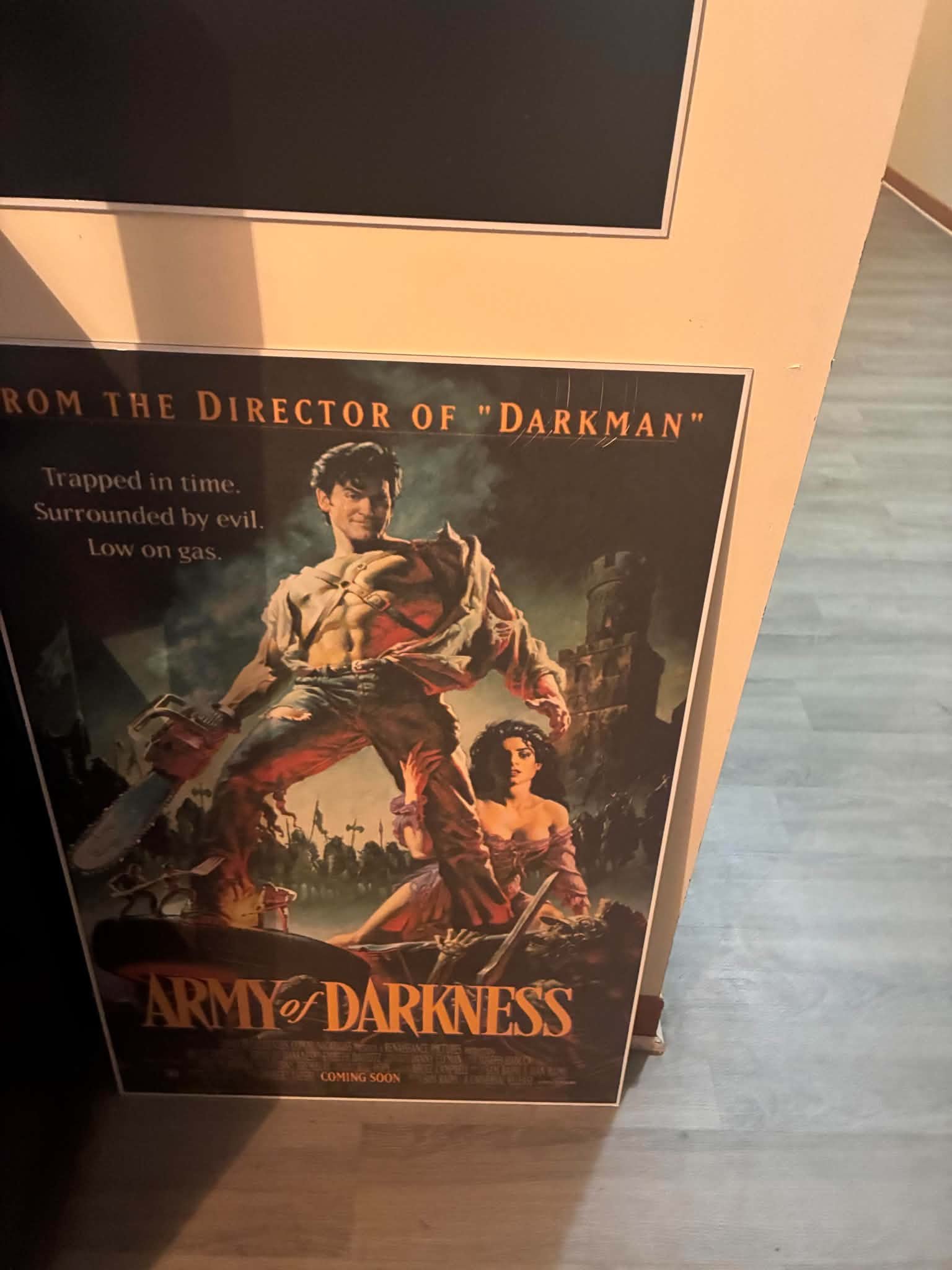 Photo of an Army of Darkness print of Ash with a chainsaw hand in front of a ruined castle, tagline reads Trapped in time. Surrounded by evil. Low on gas.