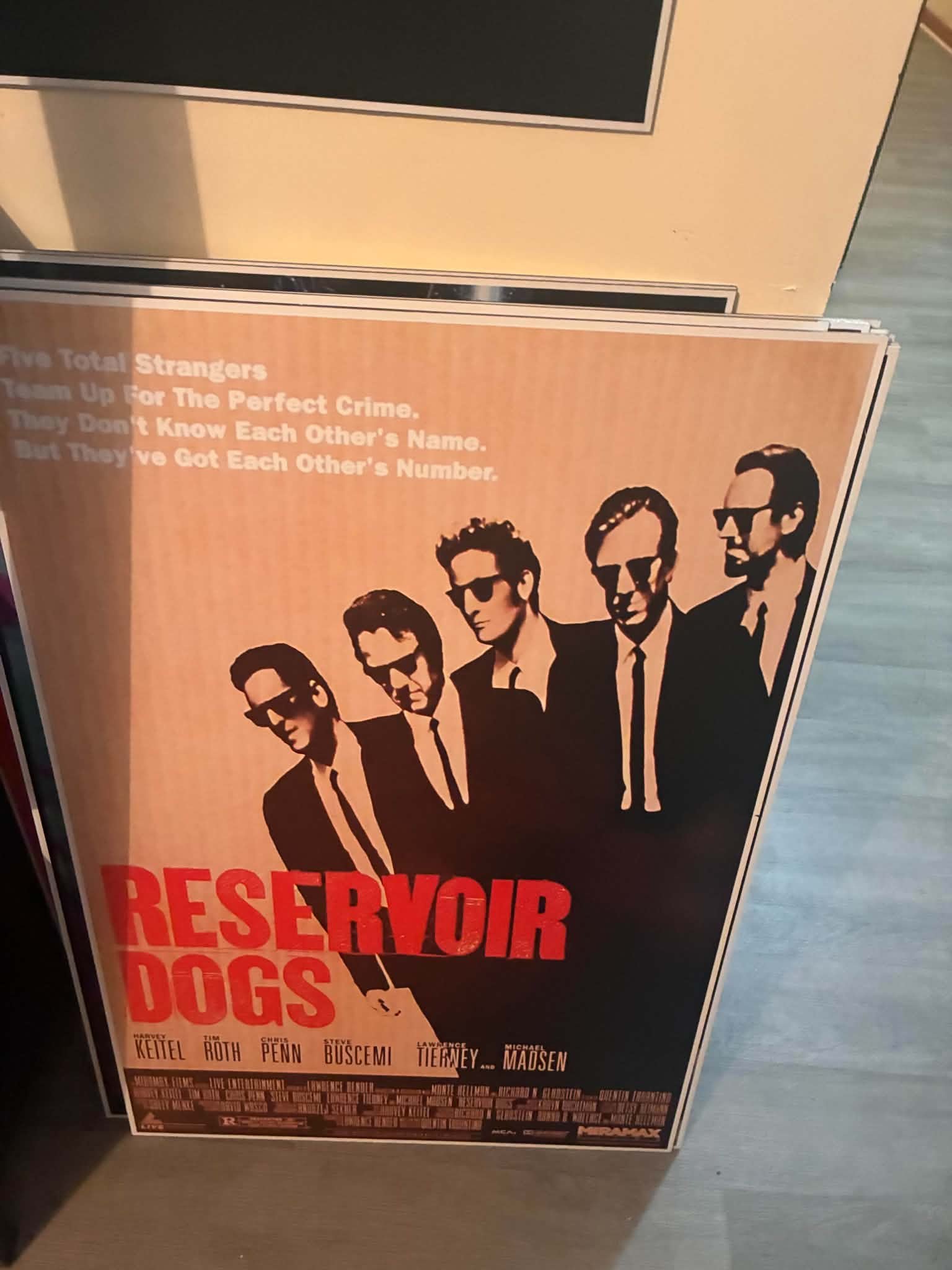 Photo of a Reservoir Dogs poster print with the five suited criminals striding in a row across an orange and black background