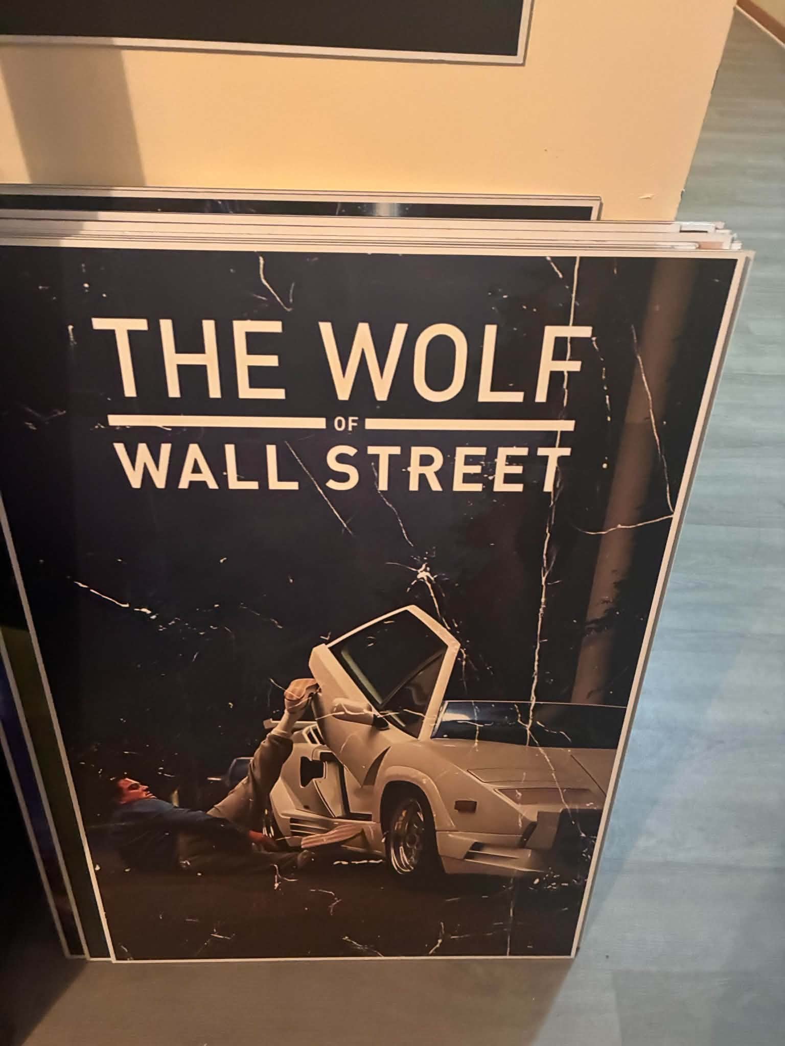 Photo of a The Wolf of Wall Street poster print with the white Lamborghini scene under a black title card
